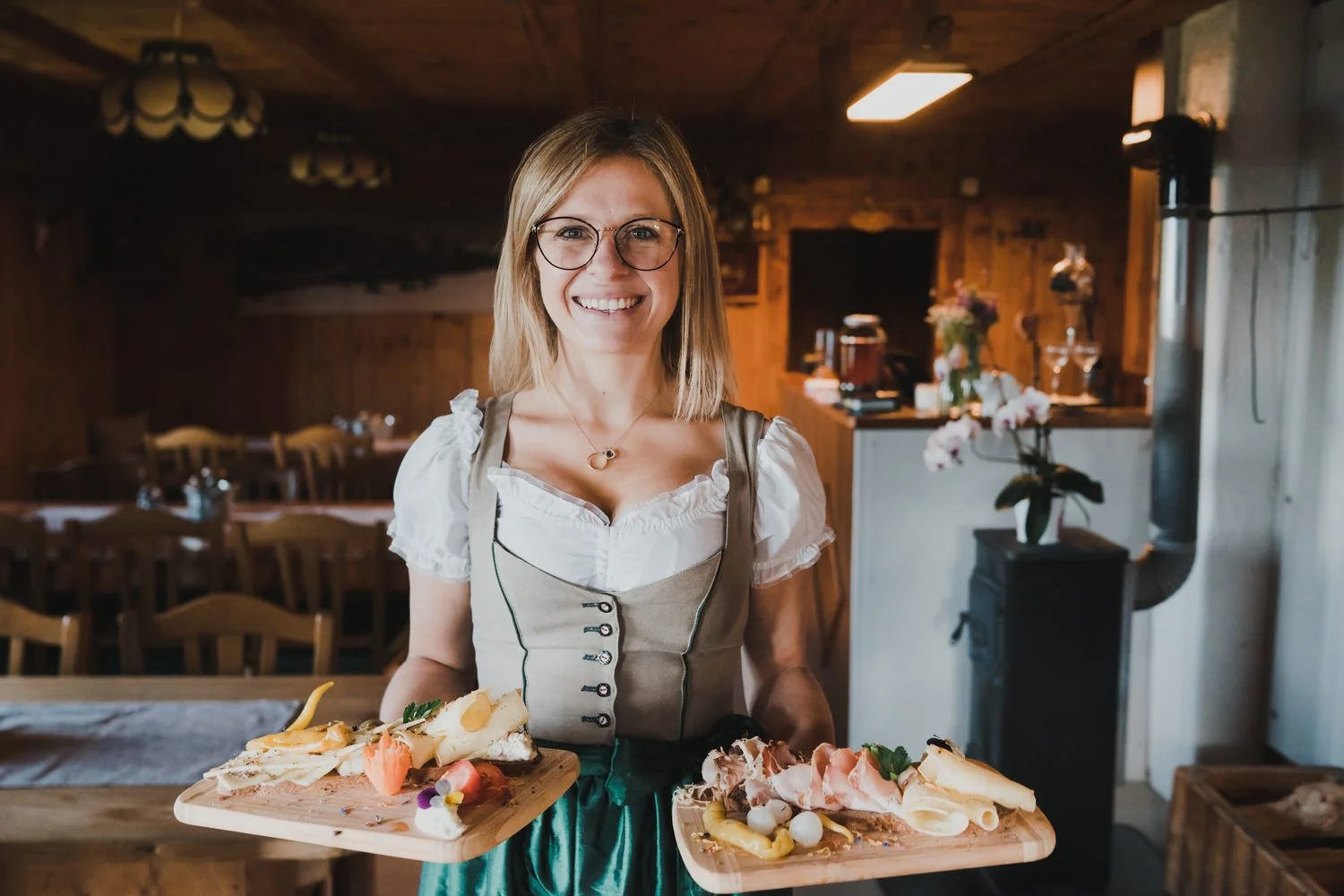 Gastgeberin mit zwei Jausenbrettern in der Stube